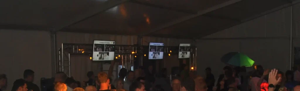 Ingezoomde foto van 3 beeldschermen boven de bar.